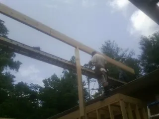 Carpenter setting a ridge beam over a new addition frame — Ice Dam Removal by Roofing Brothers in Comfrey