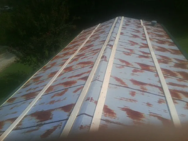 Rusted metal roof panels with new wood purlins before replacement — Storm Damage Roof Repair in Comfrey by Roofing Brothers