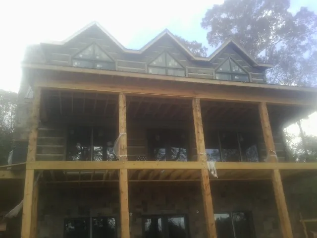 Dormers and porch framing on a large log home under construction — Roof Coating work by our crew in Comfrey