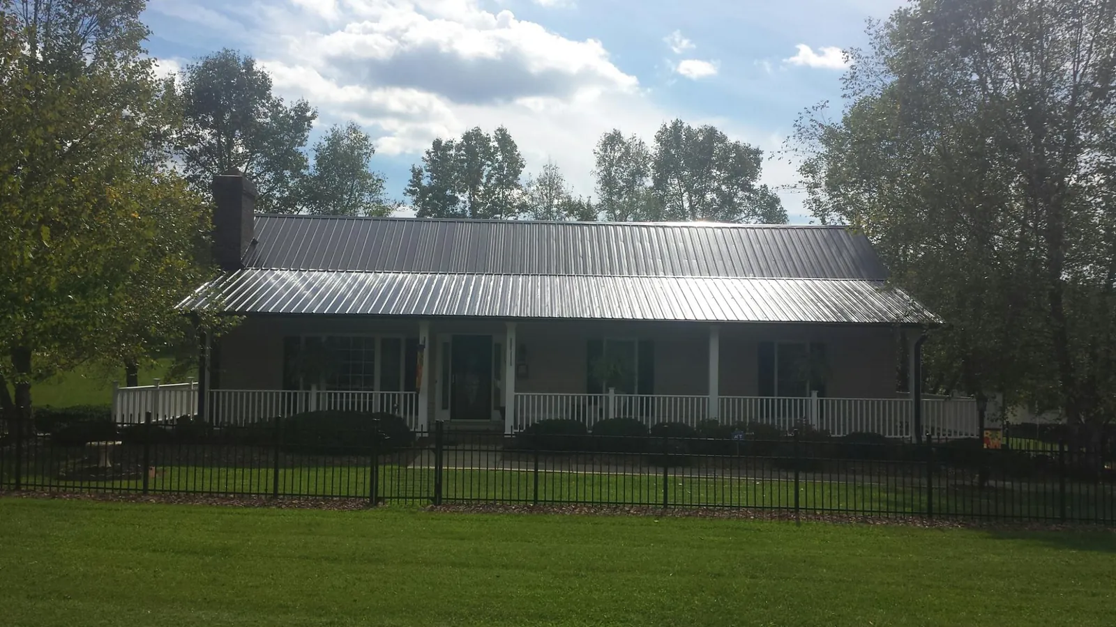 Gray metal roof on a brick ranch with a full width front porch — Gutter Guard Installation work by our crew in Comfrey