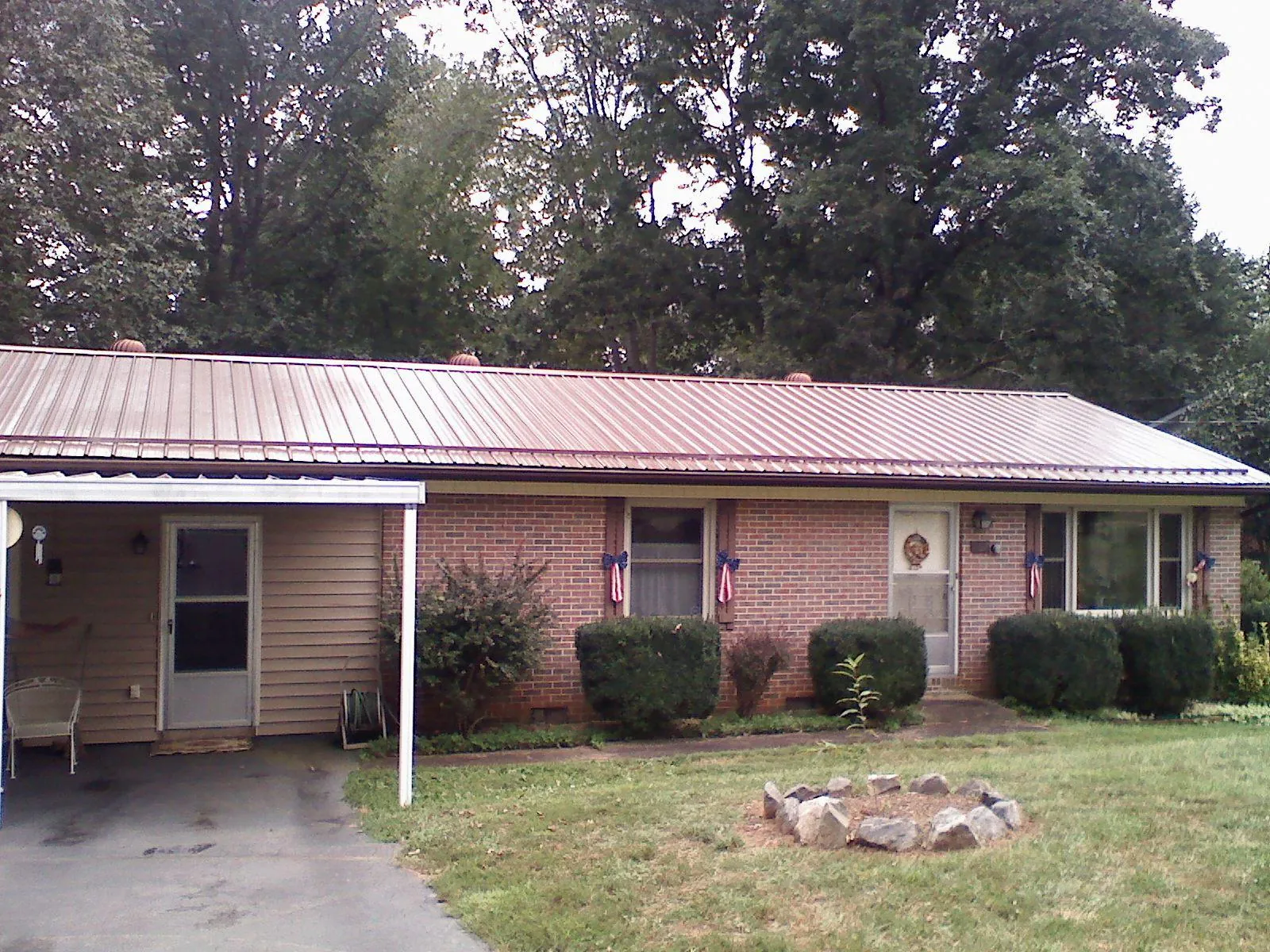 Bronze metal roof and carport on a brick ranch home — Roof Repair work by our crew in Comfrey