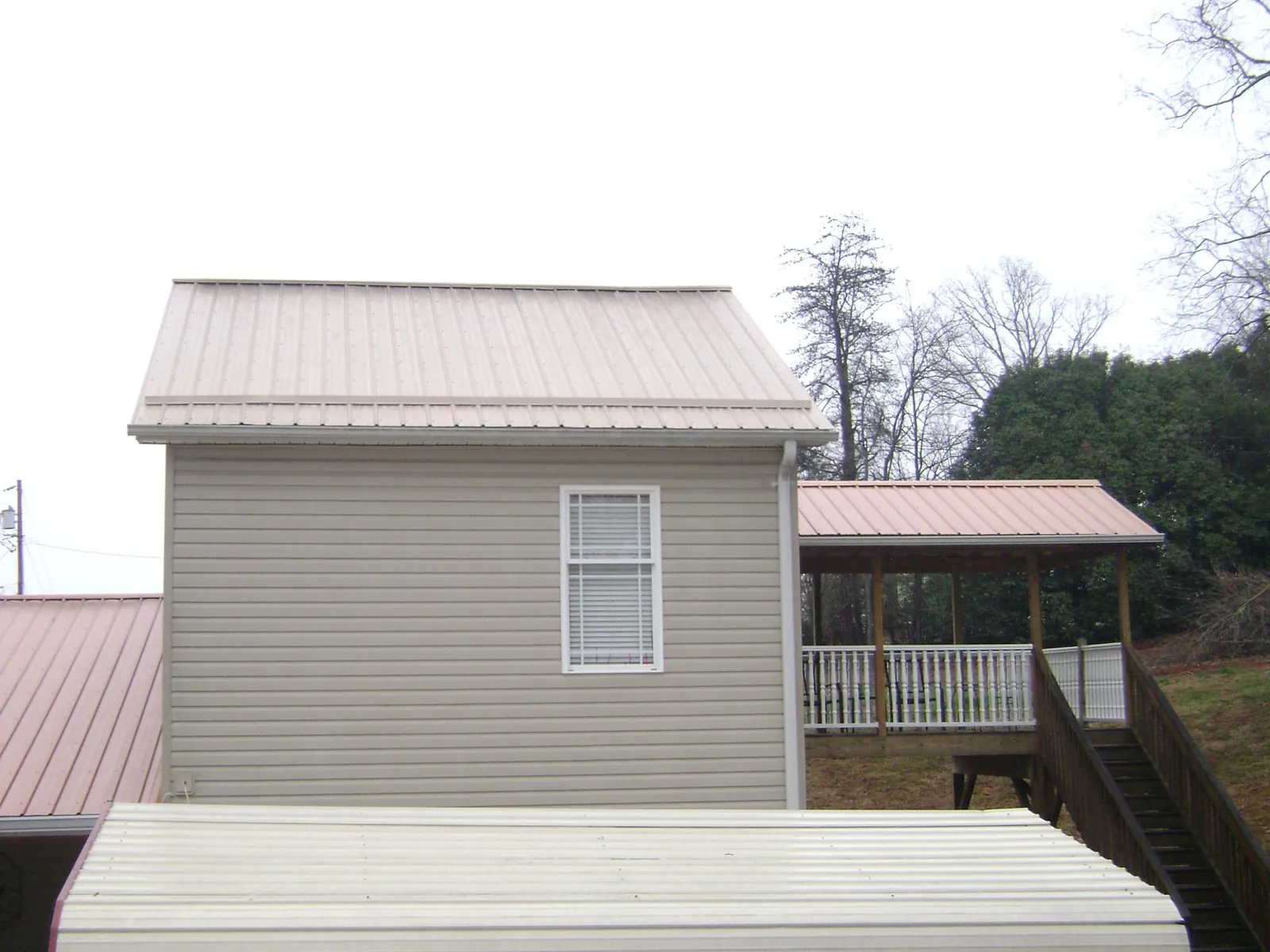 Tan metal roofs on a two story addition and attached porch, from a Roof Replacement job in Comfrey
